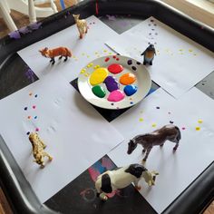 an art tray with toys and paper on it that include horses, cats, and other animals