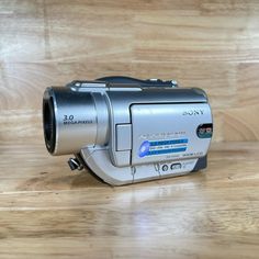 a silver camera sitting on top of a wooden table