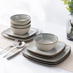 a table set with plates, silverware and flowers