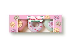 three doughnuts in a pink box with hearts on them