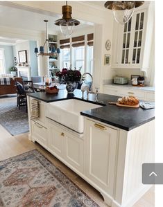 a kitchen with white cabinets and black counter tops, an area rug on the floor