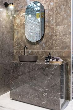 a bathroom with marble counter tops and a round mirror