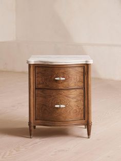 a wooden cabinet with two drawers and marble top on the bottom, against a white wall