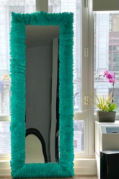 a mirror that is sitting in the middle of a room next to a vase with flowers