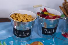 two buckets filled with different types of food on top of a blue table cloth