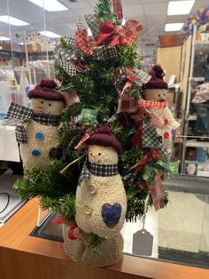 a group of snowmen sitting on top of a wooden table next to a christmas tree