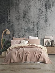 a bed with purple linens and pillows in front of a concrete wall, surrounded by potted plants