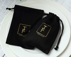 two black pouch bags sitting on top of a white plate