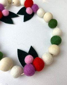 a close up of a bracelet made out of beads and felt flowers on a white surface