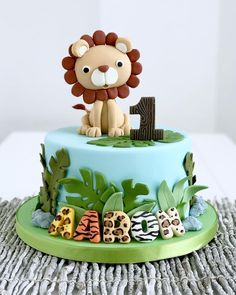 a birthday cake with a lion on top and jungle animals around the bottom tiers