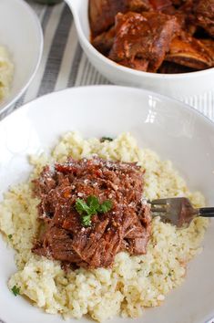 a white bowl filled with rice and meat on top of a table next to other dishes