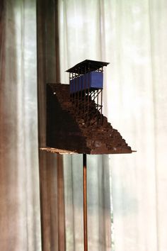 a sculpture that is sitting on top of a wooden stand in front of a curtain