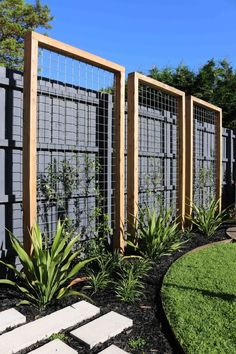 an outdoor garden area with various plants and stone walkways in front of the fence