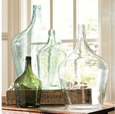 three glass bottles sitting on top of a wooden table next to a window sill