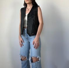 Fun and trendy vintage black-colored leather vest from the 90s, so cute! In good vintage condition. Unisex item. Measurements taken while item is laid flat. Measurements: bust: 22" length: 23.5" Tag size: XS (men's) Fabric: Leather Model is 5'6 with a waist 26" and hips 36" FOLLOW US ON INSTAGRAM @theweathereddaisy FOR RELEASE DATES + STORY SALES! SHOP OUR WEBSITE theweathereddaisy.com FOR EVEN MORE EXCLUSIVE APPAREL. Fitted Grunge Vest For Fall, 90s Sleeveless Vest For Fall, Vintage Black Vest For Spring, Black Vintage Vest For Spring, Y2k Black Vest For Streetwear, Y2k Streetwear Black Vest, Vintage Black Vest For Streetwear, Leather Vest Outfits For Women, Leather Vest Outfit