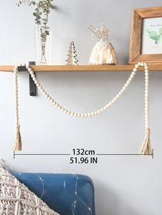 a wall shelf with beads hanging from it's sides and a vase on top