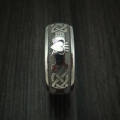 This Titanium ring features: - A Stipple and Polish Finish - A Claddagh Celtic Design - A Domed Design - 8mm Width Our Titanium rings will not tarnish or cause your skin to discolor. This ring can be fully customized! If you need to change any aspect of the ring, please contact us and we can help you out! If you have any other questions at all, please let us know! All rings will come with our standard Logo engraved on the inside of the ring. (Except for rings with wood sleeves) Buy with confiden Symbolic Etched Jewelry For Promise, Symbolic Stainless Steel Engraved Ring For Anniversary, Symbolic Etched Rings For Promise, Silver Etched Jewelry For Promise, White Gold Etched Promise Ring, Sterling Silver Engraved Promise Band, Symbolic White Gold Engraved Ring, Engraved Sterling Silver Promise Band, Symbolic Etched Promise Ring