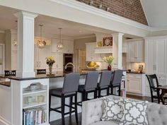 a living room filled with furniture next to a kitchen and dining room table in front of a brick wall