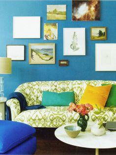 a living room with blue walls and pictures on the wall, including a white coffee table