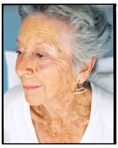 an older woman with gray hair and large hoop earrings on her ear, looking at the camera