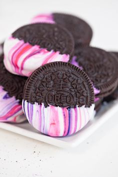 oreo cookies with pink and purple swirled frosting on a white square plate, ready to be eaten