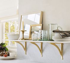 a white table topped with plates and bowls next to a wall filled with framed pictures