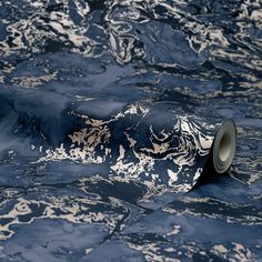 a roll of black and white marbled paper on the ground with an object in it's center