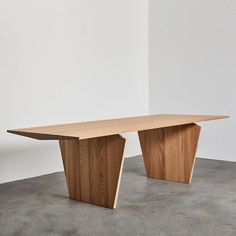 a large wooden table sitting on top of a cement floor next to a white wall