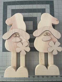 two wooden pegs with faces and hearts on them, sitting next to a ruler