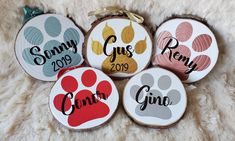 four personalized wood slices with dog paw prints and names on them, sitting on a white fur surface