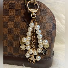 a handbag with pearls and charms hanging from it