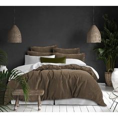 a bed with brown and white comforters in a room next to plants on the floor