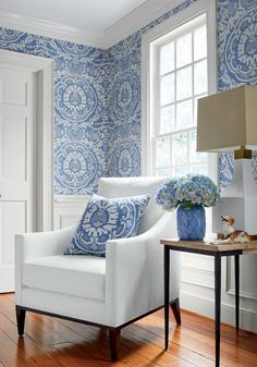 a living room with blue and white wallpaper on the walls next to a chair