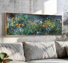 a painting hanging on the wall above a couch in front of a potted plant