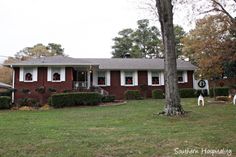 a red brick house with white shutters and christmas decorations on the front porch is shown