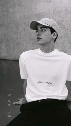 black and white photograph of a young man wearing a baseball cap sitting on a bench