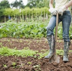 a woman holding a shovel while standing in the dirt