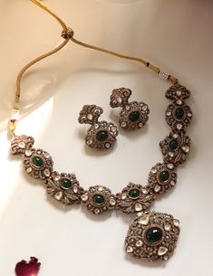 Inspired by the romantic Victorian era, this elegant necklace set is a true masterpiece. Encrusted with sparkling polki stones and adorned with cubic zirconia for added brilliance, it features emerald green stones that add a touch of color and allure. Accompanied by matching earrings, this set is the perfect choice for a formal occasion, exuding timeless charm and sophistication. Finish: Rhodium Plating Material: Silver, Copper Alloy, Emerald, Polki & CZs Color: Green Size: Free Size, Adjustable Luxury Hand Set Kundan Necklace, Traditional Hand-set Emerald Diamond Necklace, Traditional Hand-set Diamond Emerald Necklace, Elegant Emerald Kundan Necklace For Festive Occasions, Elegant Kundan Emerald Necklace For Festive Occasions, Elegant Silver Kundan Necklace With Emerald, Elegant Emerald Kundan Necklace For Gift, Elegant Jeweled Green Emerald Necklace, Elegant Green Kundan Necklace