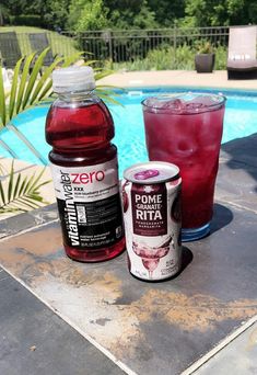 two sodas next to each other near a swimming pool with trees in the background