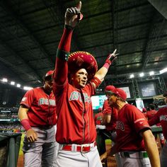 the baseball players are wearing red hats and waving their hands in the air as they walk off the field