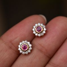 "Crafted in solid 14k gold, these earrings are bezel set with natural round Ruby in the center, with a natural diamond floral halo. Perfect pair for everyday wear or for a special occasion, a must-have piece for every wardrobe. A great gift for a July born. Can be worn in almost all piercings like nose, tragus, helix, lip, lobe, flat, conch, brow, dermal, etc * Flower Size : 7.5 mm * Gemstone 1: Natural Diamond * Diamond Wt. : 0.20 Ct * Color / Clarity : H-I, Vs-Si * Gemstone 2: Ruby * Stone Wt. July Born, Floral Halo, Ear Ring, Bridal Gold Jewellery Designs, Diamond Earring, Ruby Earrings, Ruby Stone, Earrings Studs, Birthstone Earring