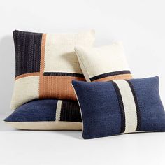 three pillows on top of each other in different colors and sizes, one with a striped design