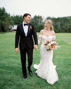 a bride and groom walking through the grass