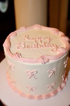 a birthday cake with pink icing and bows on it sitting on a white plate