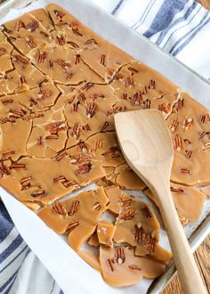 a wooden spoon sitting on top of a pan filled with caramel pretzels