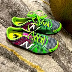 a pair of new balance running shoes sitting on the ground next to a green ball