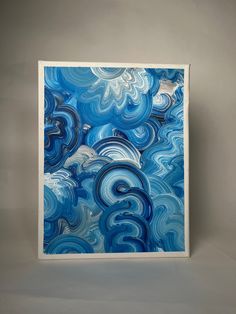 an abstract painting in blue and white with swirls on the bottom, against a gray background