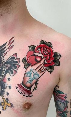 a man with tattoos on his chest holding a rose and two birds in front of him