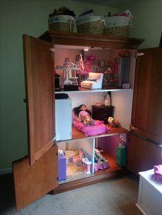 an open cupboard with dolls in it and other items on the floor below, inside