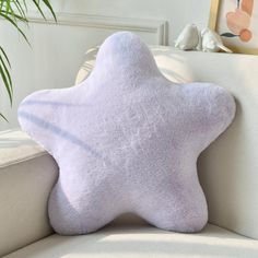 a white star pillow sitting on top of a couch next to a potted plant